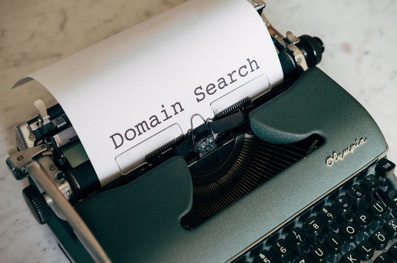 A typewriter with Domain Search typed on paper, symbolizing the process of choosing the right web address