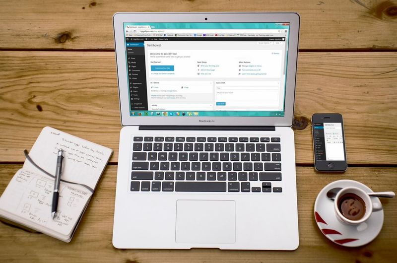 A workspace with laptop and notebook, where WordPress SEO plugins like Rank Math and Yoast are configured