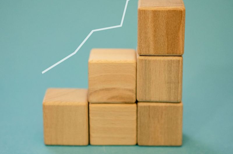 Wooden blocks forming a staircase with an upward arrow, symbolizing property value growth through real estate SEO