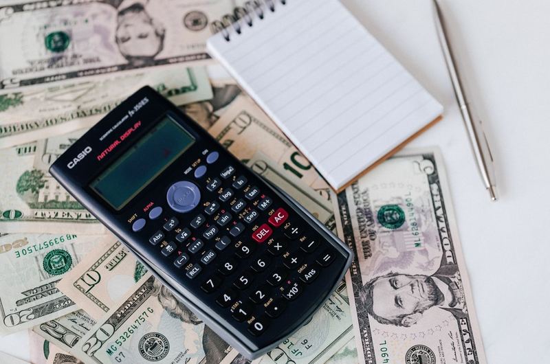 A calculator and notepad alongside currency, representing the investment planning for SEO services