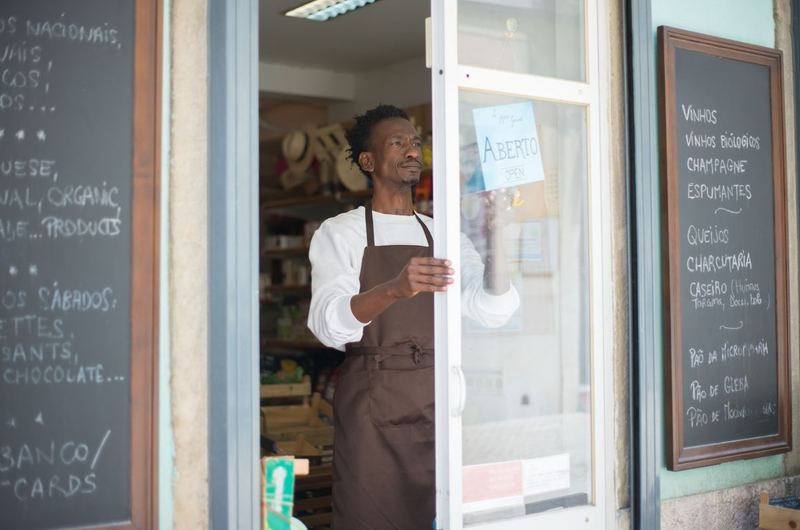 A small business owner opening his shop door, the type of local entrepreneur who benefits from SEO