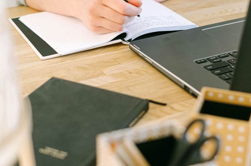 A writer taking notes while researching on a laptop, part of the process for crafting ranking blog content