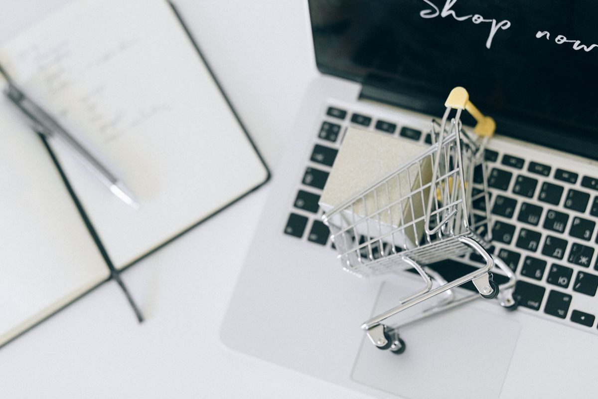 A miniature shopping cart beside a laptop, symbolising a Nepali online store