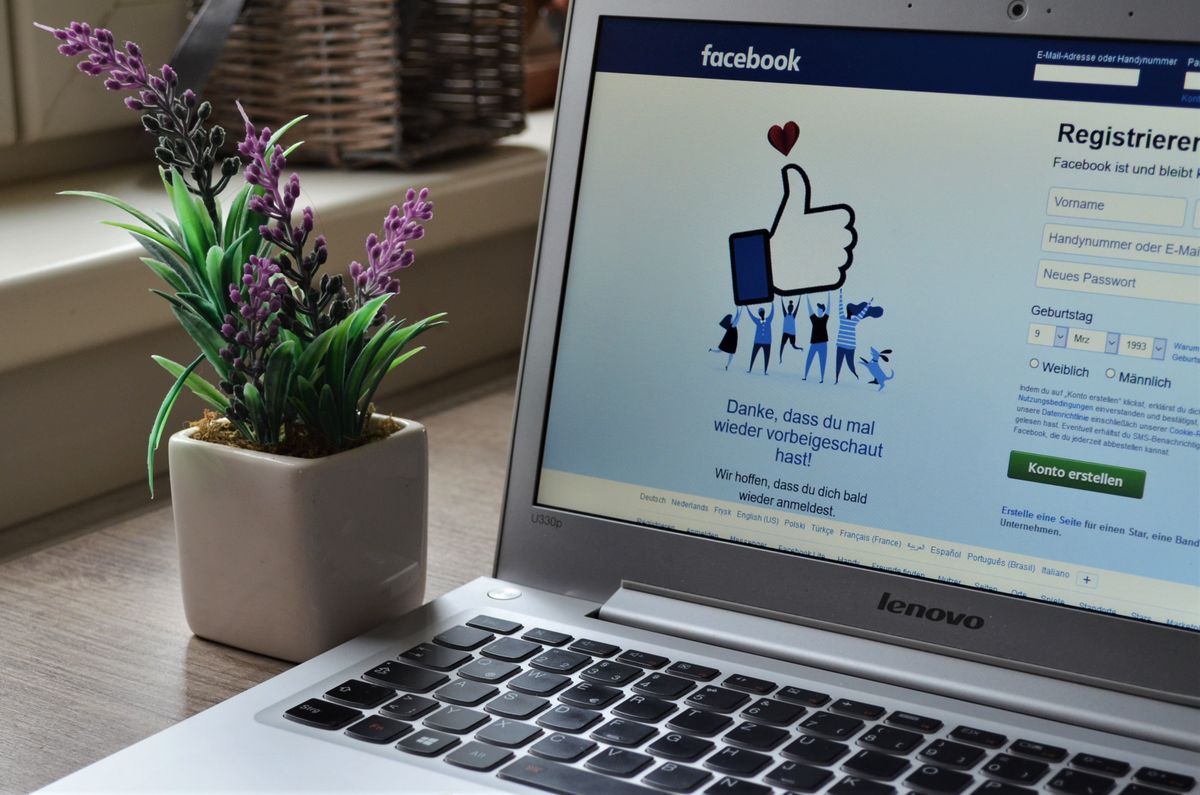 A laptop open to the Facebook sign-up page next to a small plant, representing a business setting up Facebook advertising