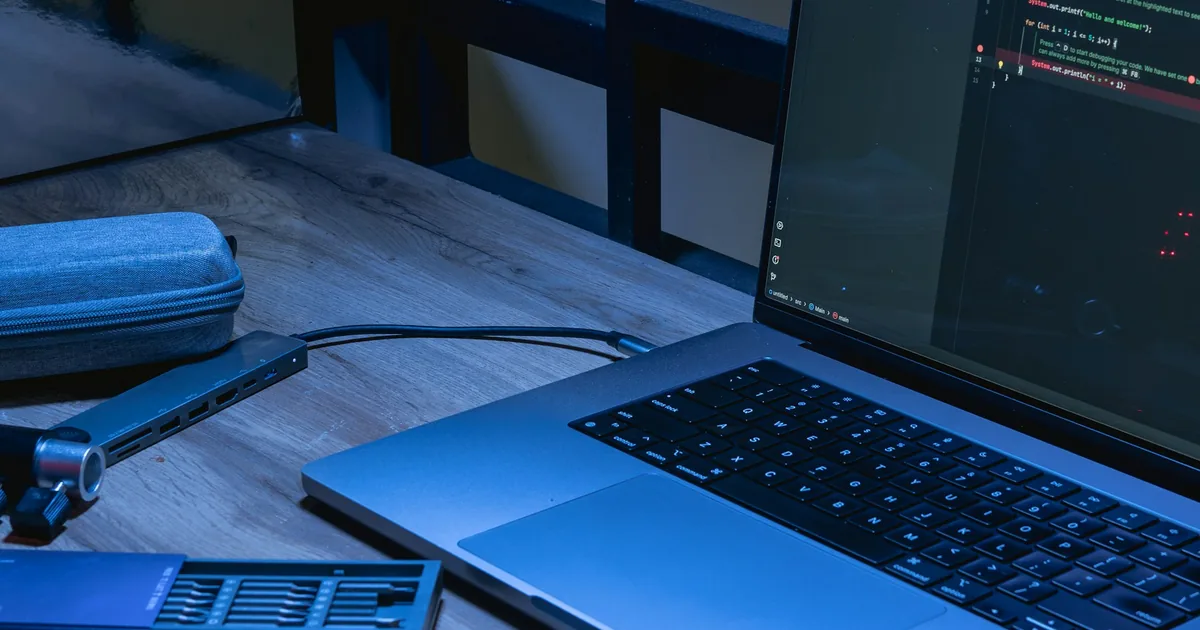 Laptop displaying source code on a desk, illustrating React interaction debugging.
