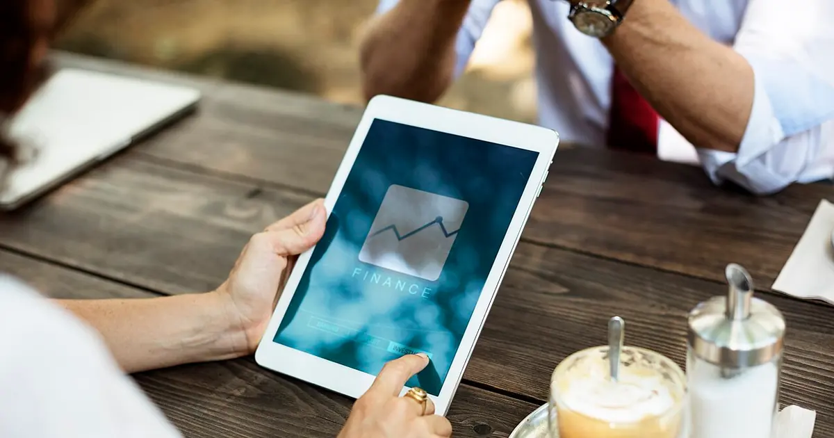 Person reviewing figures on a tablet over coffee, illustrating an SEO investment decision