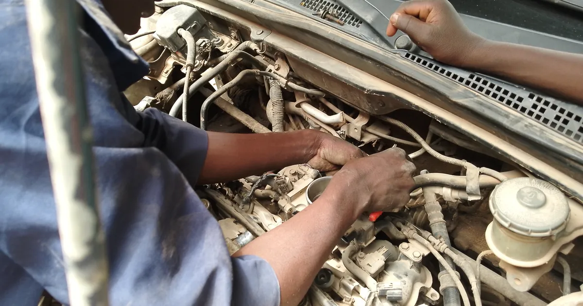 Mechanic's hands repairing a car engine under the open bonnet