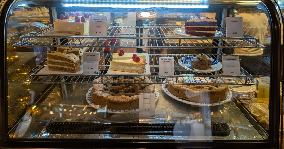 Glass display case with slices of layer cake, cheesecake and pies, each with a price label
