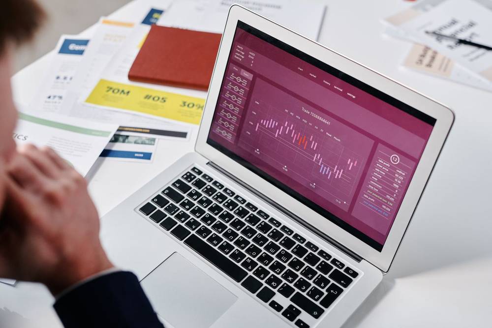 Business professional reviewing data analytics on a laptop screen showing charts and metrics