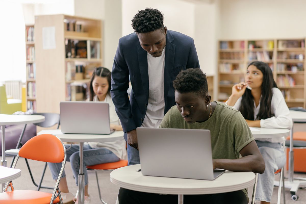 A counsellor guiding a student at a laptop in a study space, the advising work at the heart of an education consultancy