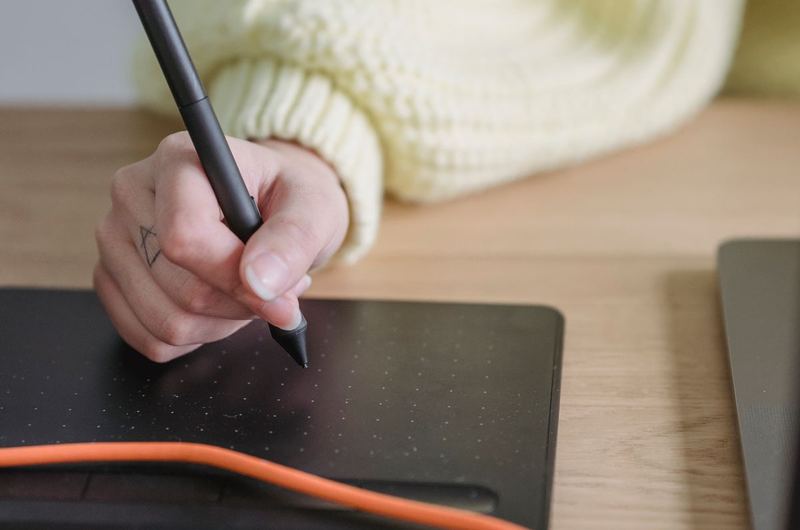 A person using a digital drawing tablet and stylus, representing hands-on tool usage